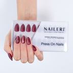 Mano con le press on nails Berry Cat's Eyes applicate, accanto alla confezione NAILERÌ