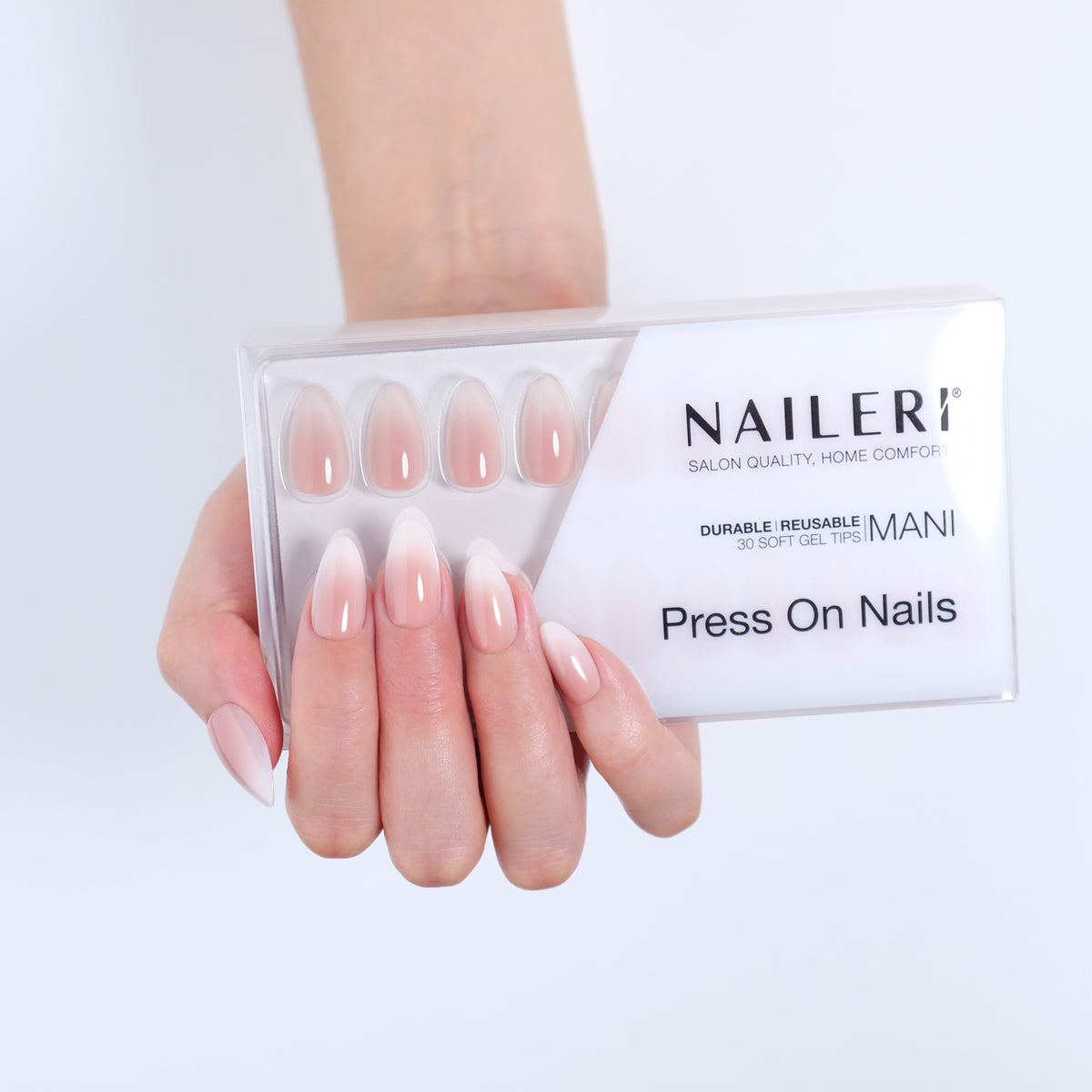 Mano con le press on nails Nude Babyboomer forma mandorla applicate, accanto alla confezione NAILERÌ