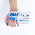 Mano con le press on nails Pacific Cat's Eyes forma mandorla applicate, accanto alla confezione NAILERÌ
